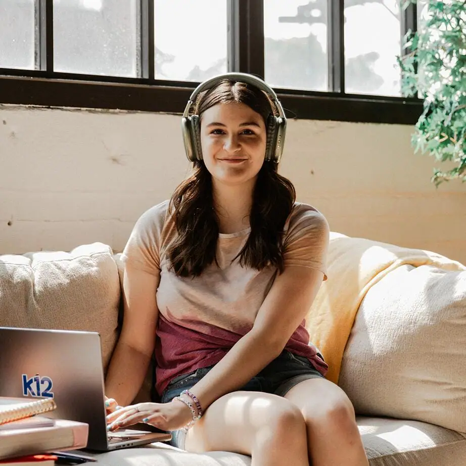 طالبة ترتدي زوجًا من سماعات الرأس أثناء استخدامها للكمبيوتر المحمول