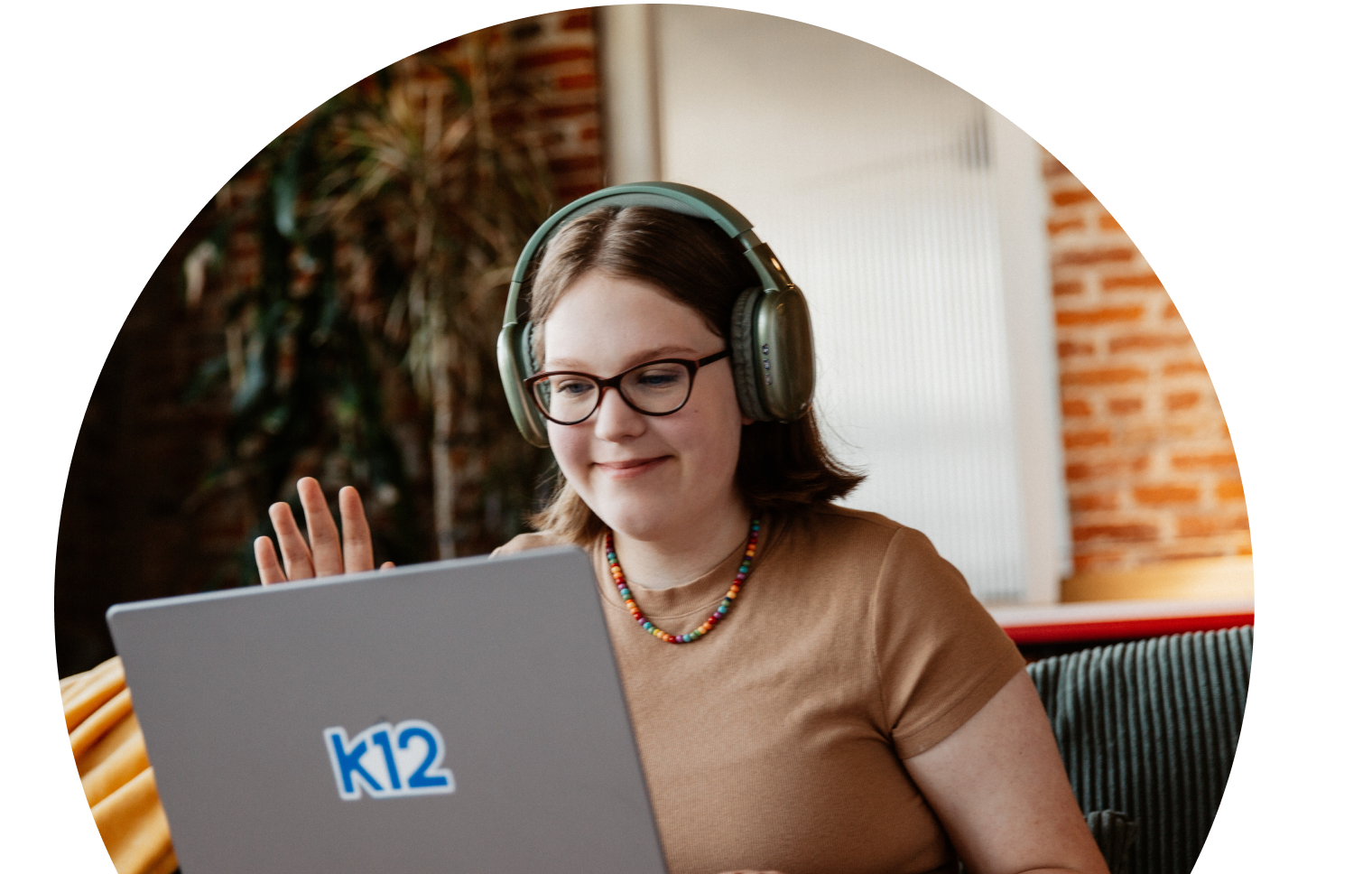 طالبة تحمل حاسوبها المحمول وترتدي سماعات رأس خضراء اللون